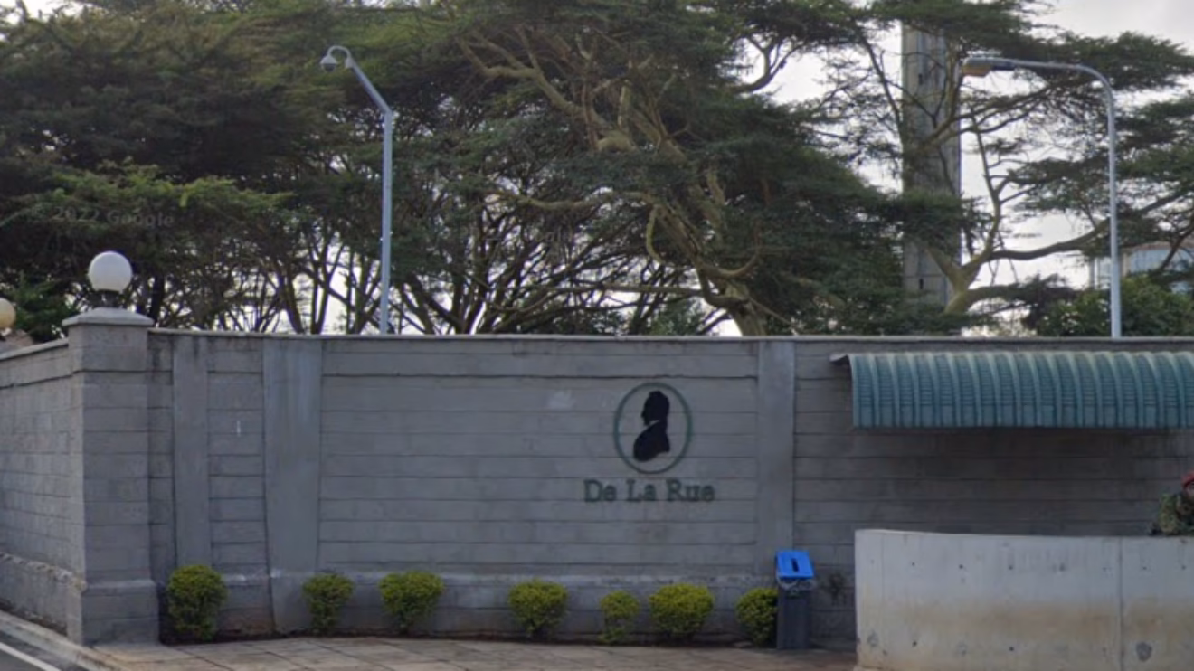 Exterior stone wall of the De La Rue Currency and Security Print premises in Nairobi, Kenya, displaying the official De La Rue logo and name.